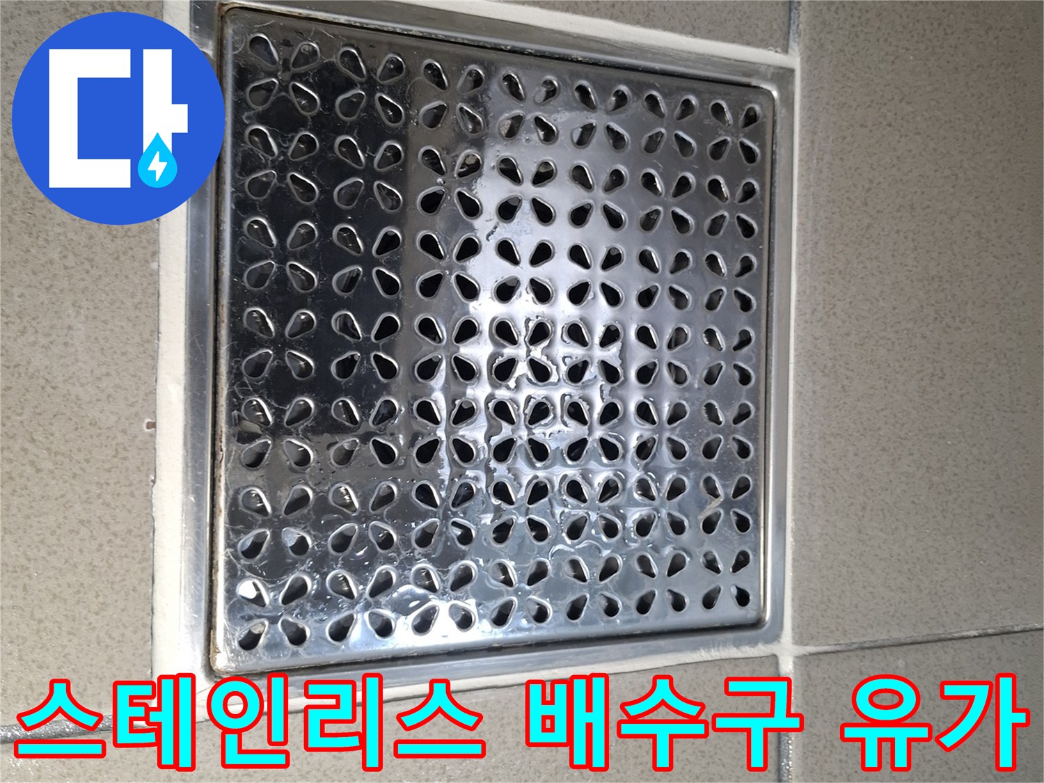 금속 재질의 화장실 배수 트랩과 주변 타일 모습