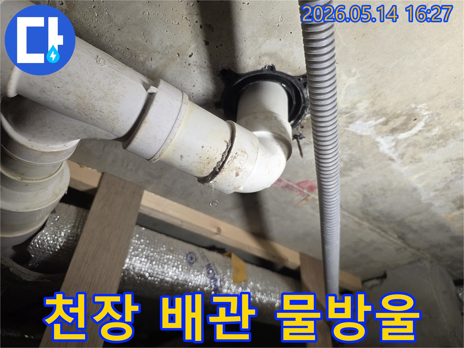 콘크리트 천장에서 내려오는 배관 이음새에서 물이 떨어지는-천장 누수 현장의 클로즈업 사진