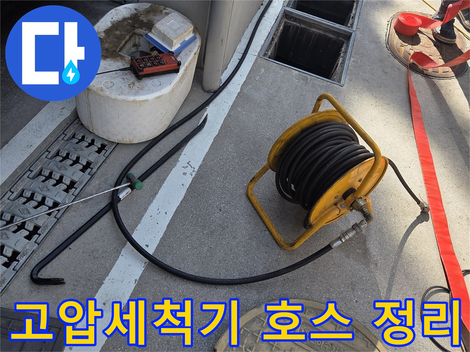 맨홀 근처에 배치된 노란색 고압 세척 호스 릴과 장비