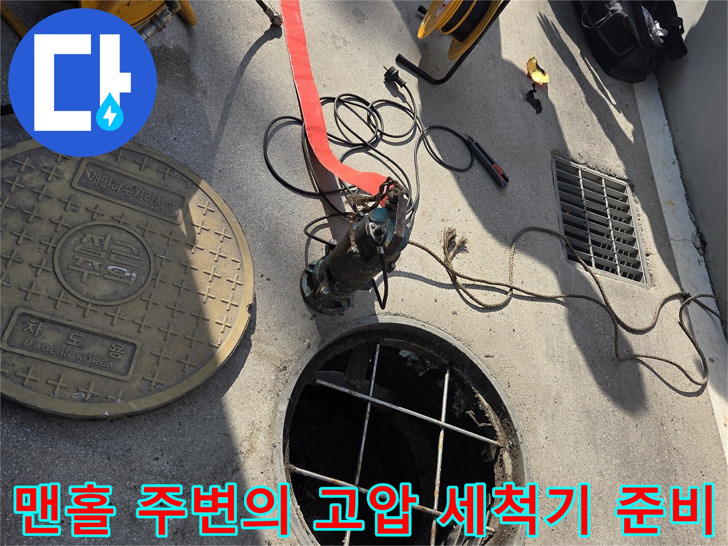 작업용 호스와 연결 장비가 맨홀 근처에 놓여 있습니다.