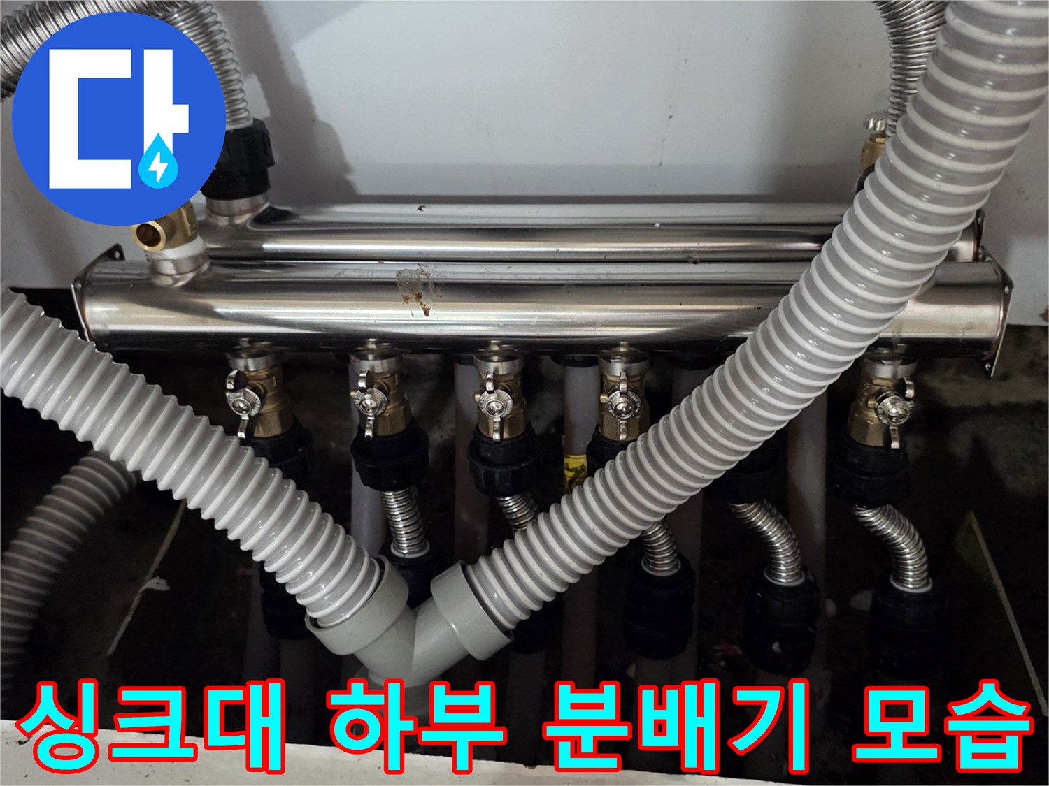 싱크대 아래 설치된 금속 재질의 보일러 분배기와 배관들입니다.