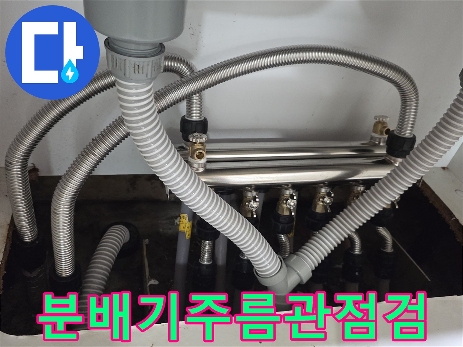 싱크대 하부장의 분배기 밸브와 연결된 은색 배관들의 모습입니다.