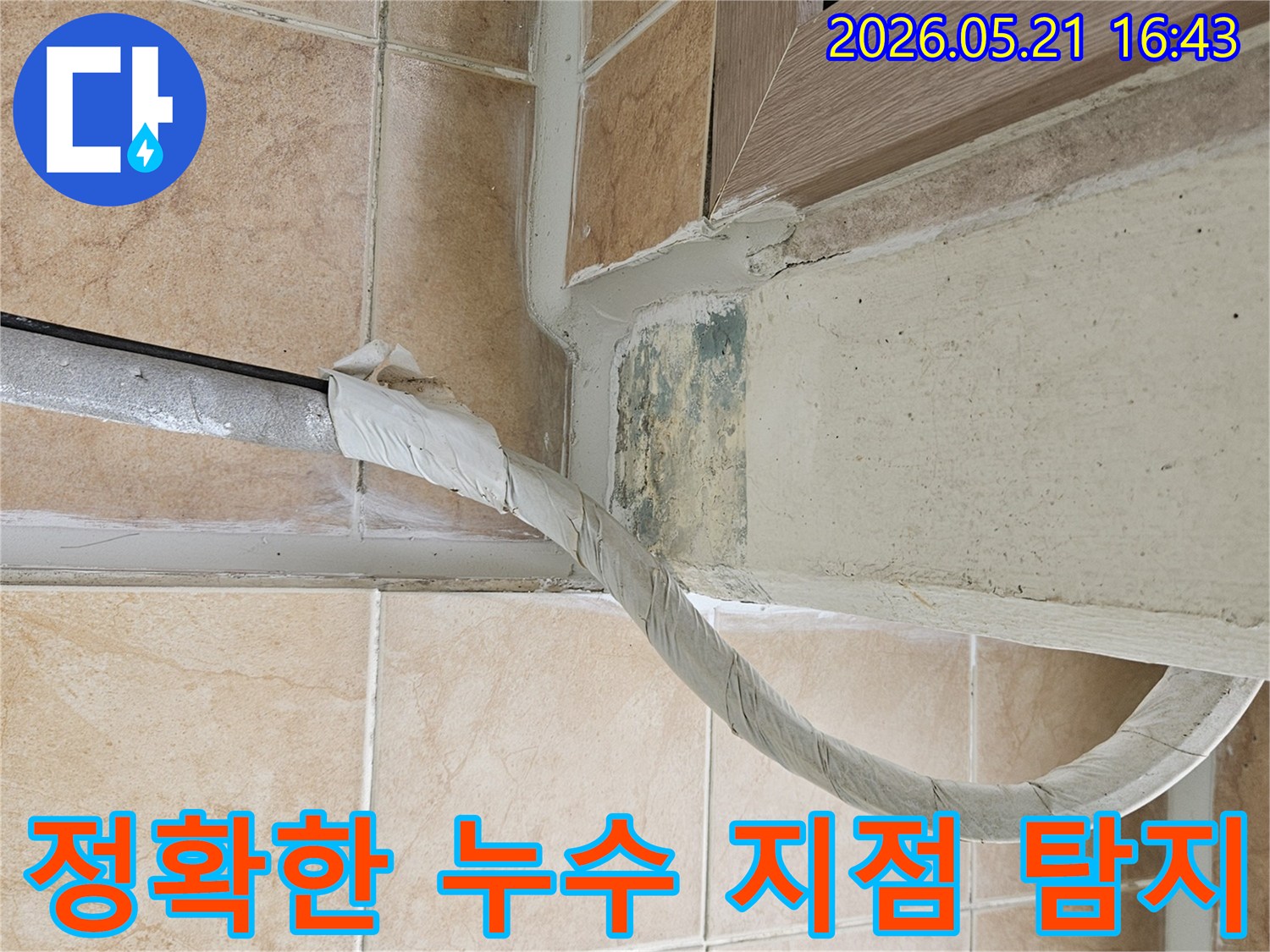 이 사진은-포천 아파트의-벽면 하단과-바닥 타일 경계에서-발견된-습기 및-곰팡이 흔적과-단열 배관의-모습을-담고 있으며-정확한-누수 지점-탐지의-필요성을-보여줍니다