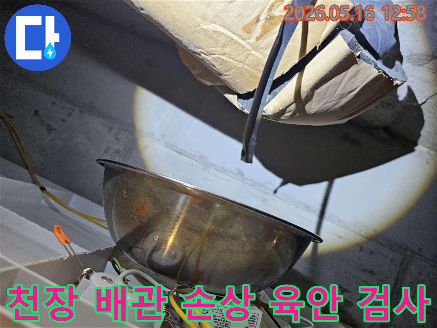천장 속 어두운 공간에서-밝은 조명으로-배관의 손상 여부를-육안으로 꼼꼼히-검사하는 모습입니다