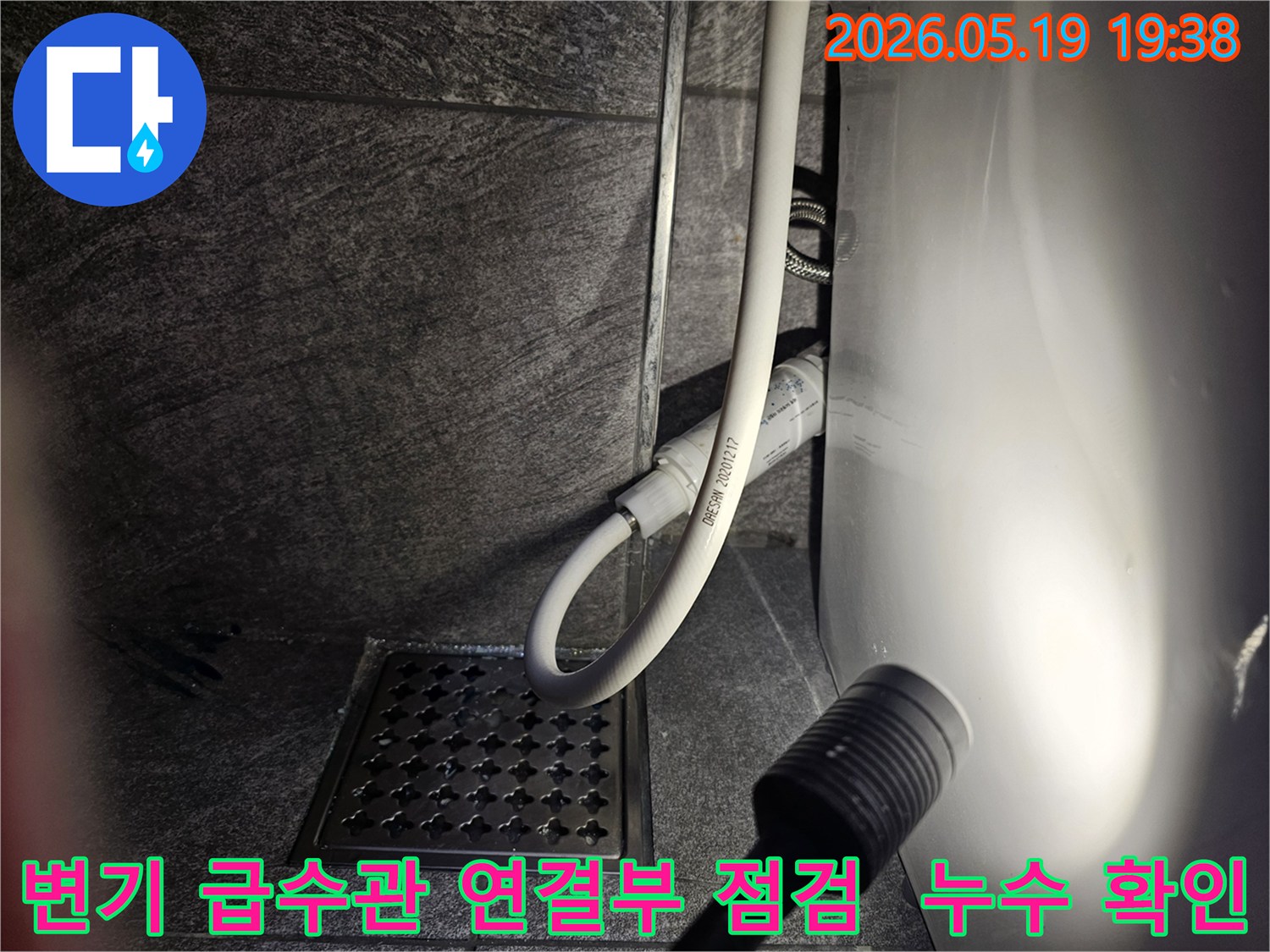 이 사진은-수지구 아파트 화장실에서-변기 급수관 연결부의 누수 여부를-플래시로 비추며-세밀하게 점검하는 현장을 보여줍니다.