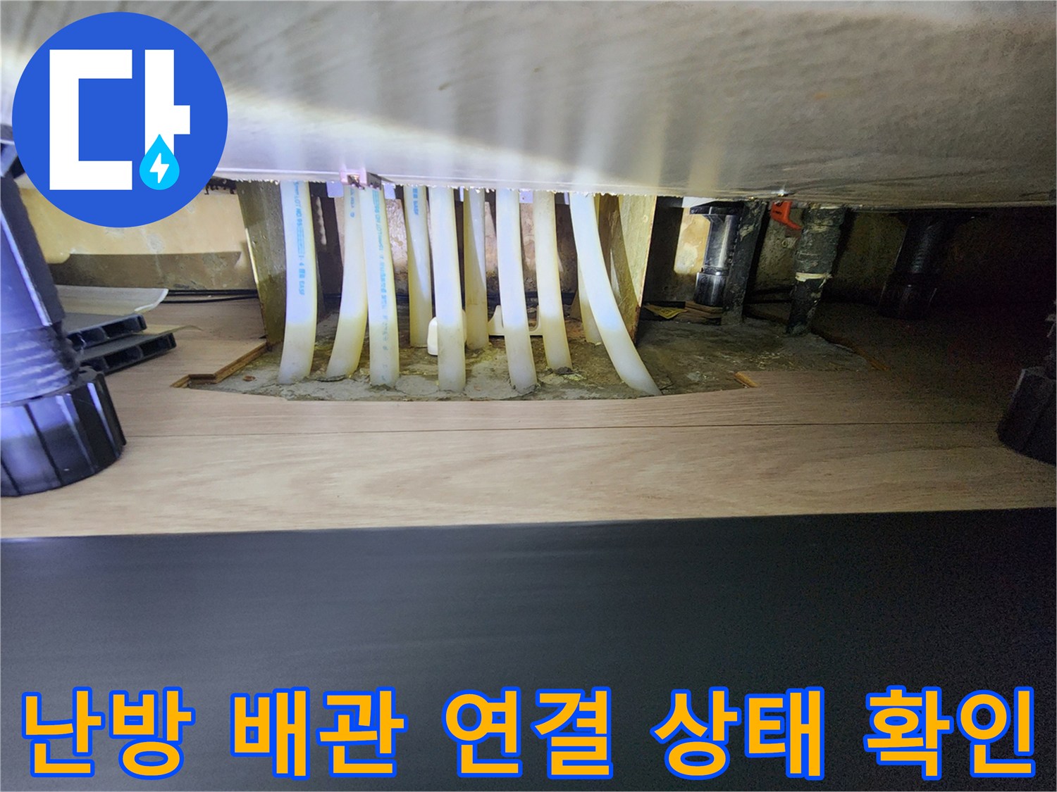 싱크대 밑 공간에 노출된 난방용 화이트 배관과 분배기 밸브들