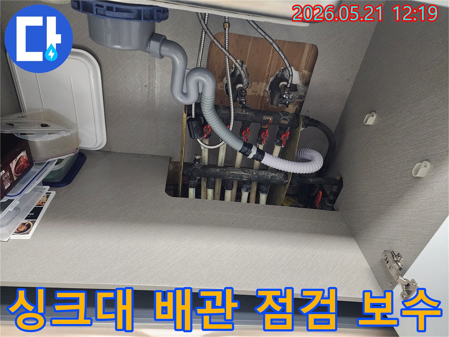 싱크대 하부의 배관과 분배기-누수 점검 및 보수 작업을 위해 촬영된 이미지입니다.