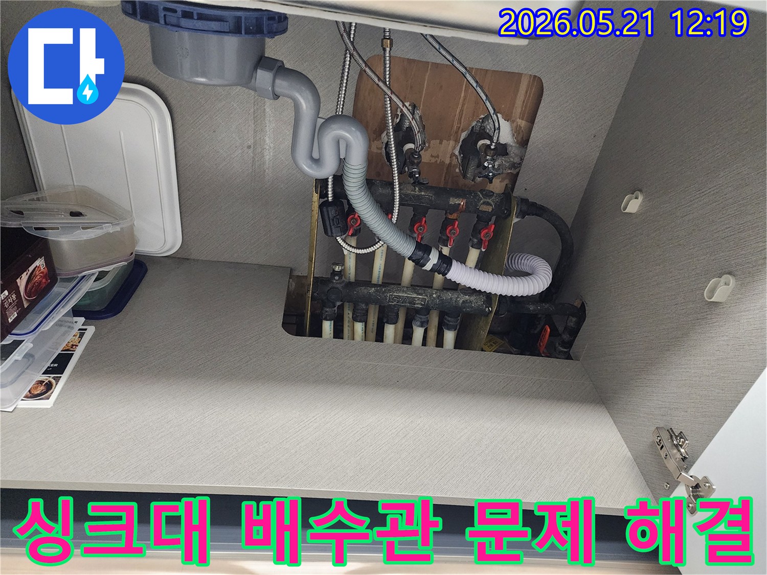 싱크대 하부의 배수관-누수 문제 해결을 위해 점검 중인 현장 사진입니다.