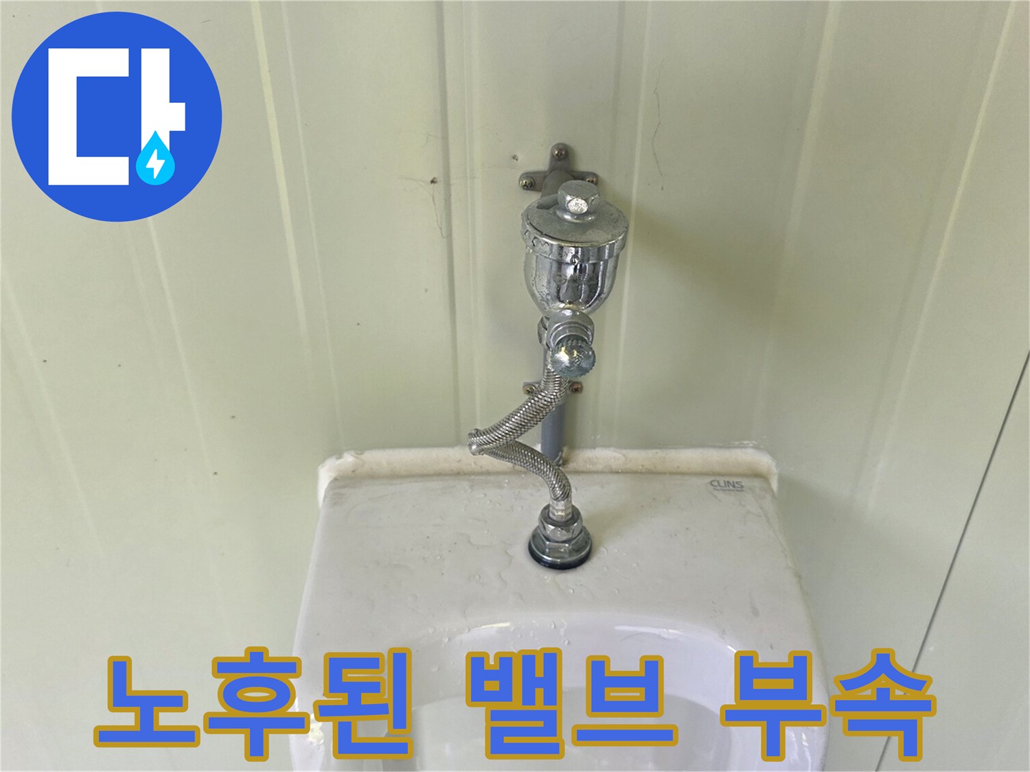 소변기 상단에 위치한 노후된 금속제 플러시 밸브