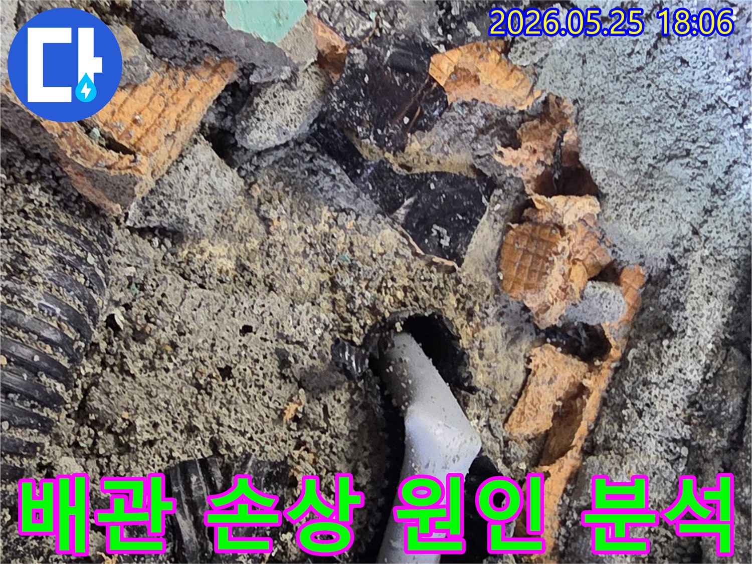 파쇄된 바닥 아래에서 드러난 젖은 배관과 주변의 흙-콘크리트 조각들은-누수 수리를 위한 배관 교체 작업을 보여줍니다.