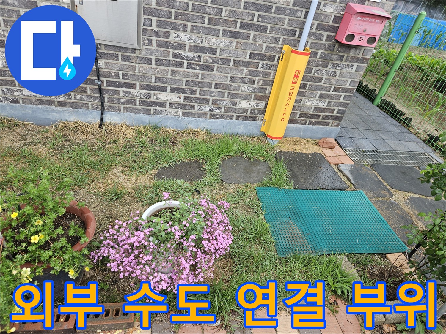 주택 외벽과 마당 경계에 있는 야외 수도 설비 이미지입니다.