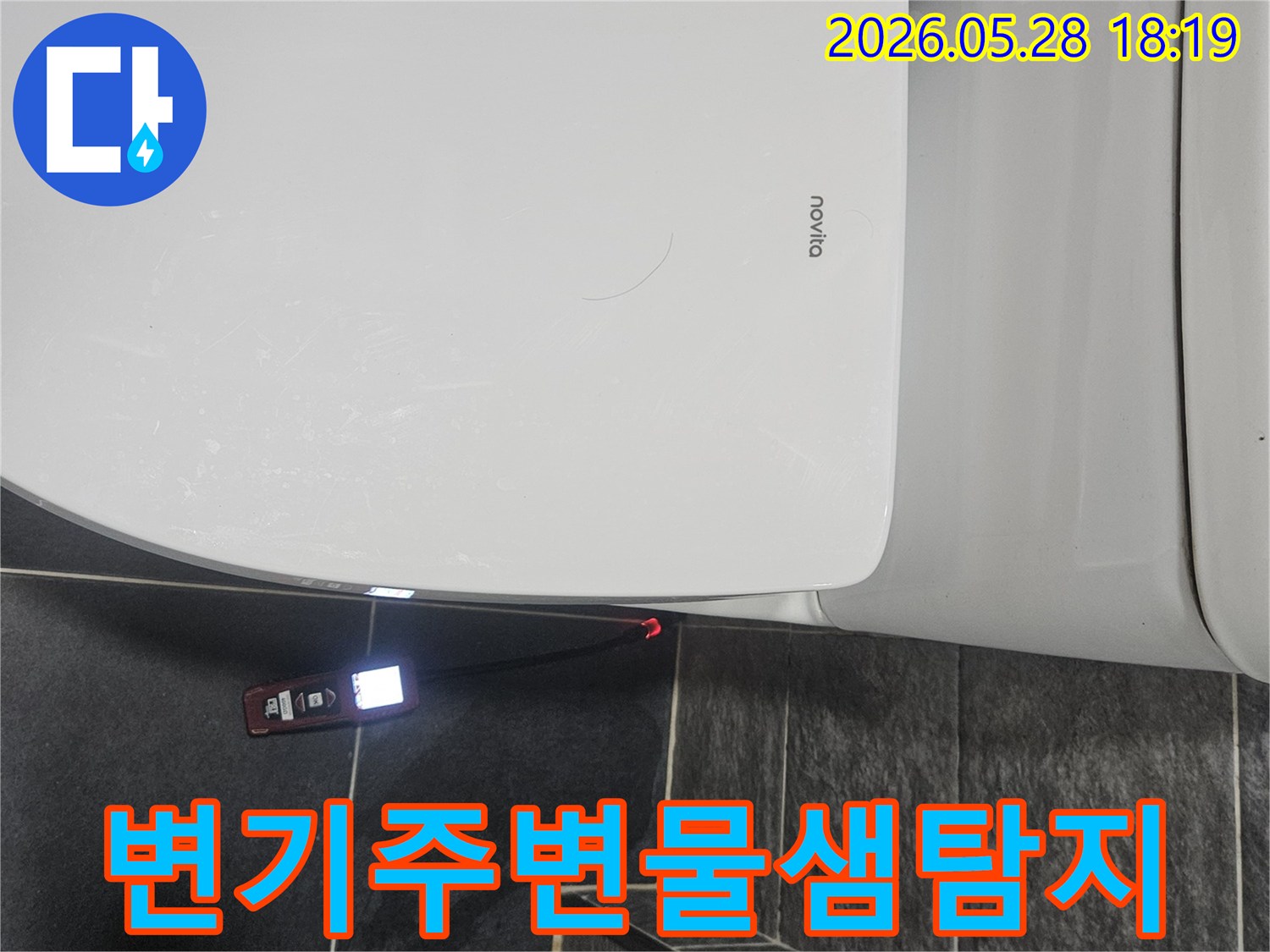 화장실 변기 옆-어두운 바닥 타일 위에서-누수 탐지기가-빨간색으로-누수 지점을 표시하고 있습니다.