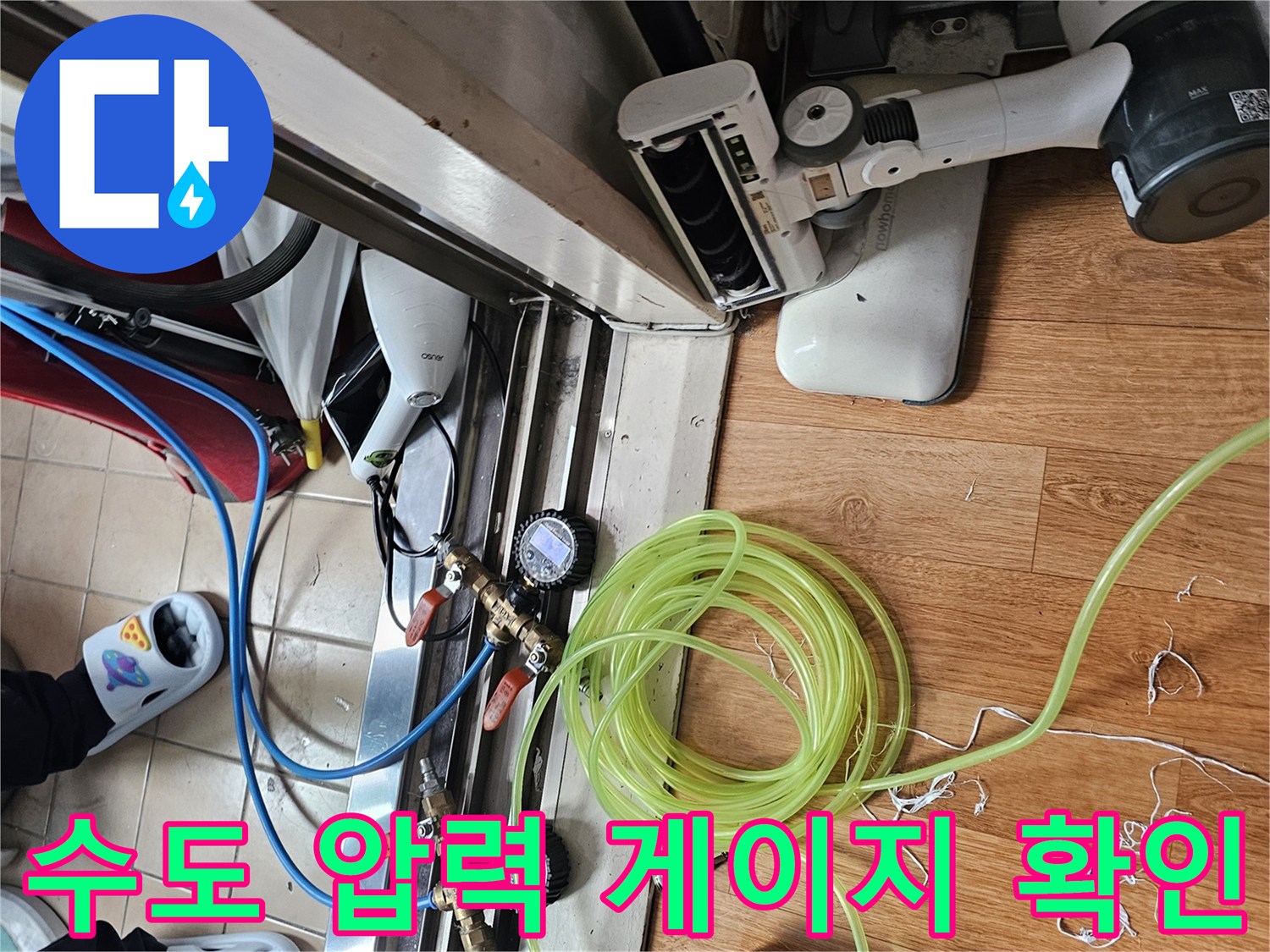 싱크대 하단 공간-누수 탐지를 위해 연결된 파란색 호스와 압력 측정기