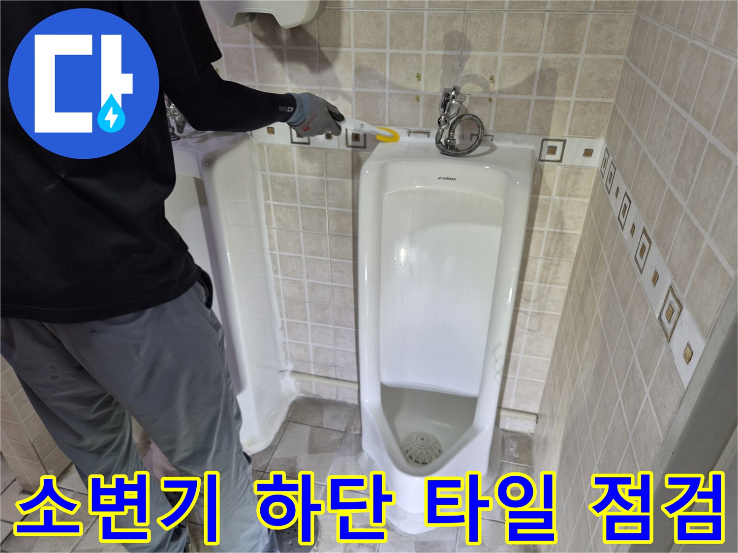 소변기 설치 부위의 타일 틈새를 정밀하게 점검하고 있습니다.