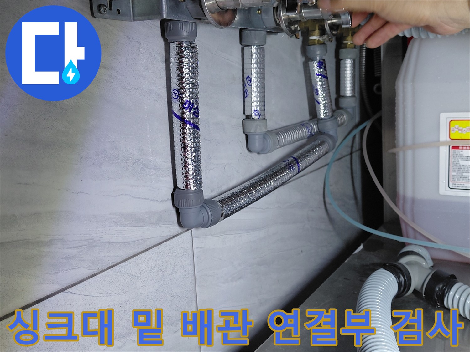 은색 보온재로 덮인 에이콘 배관과 손으로 만지는 작업자의 모습