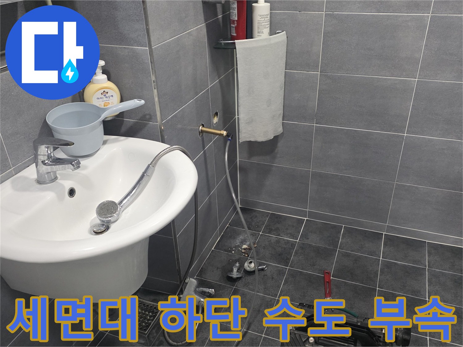 욕실 세면대 아래쪽에 설치된 은색 금속 수전과 호스