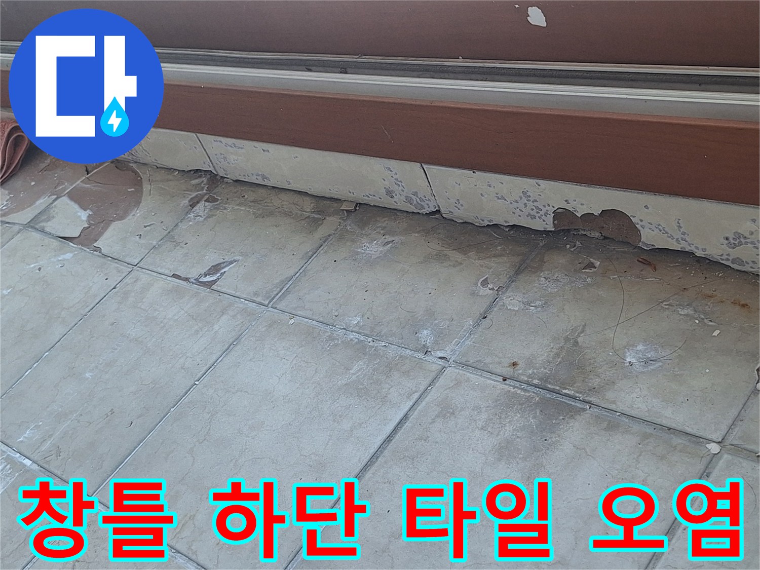 갈색 창틀 아래쪽 타일 마감재의 심한 얼룩과 벗겨짐 현상