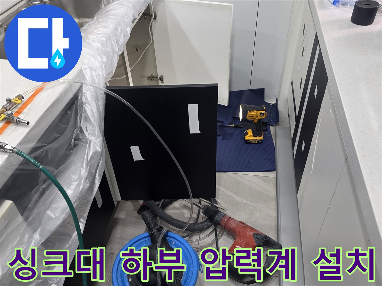 주방 싱크대 하단 배관에 연결된 공압 테스트용 압력계와 호스