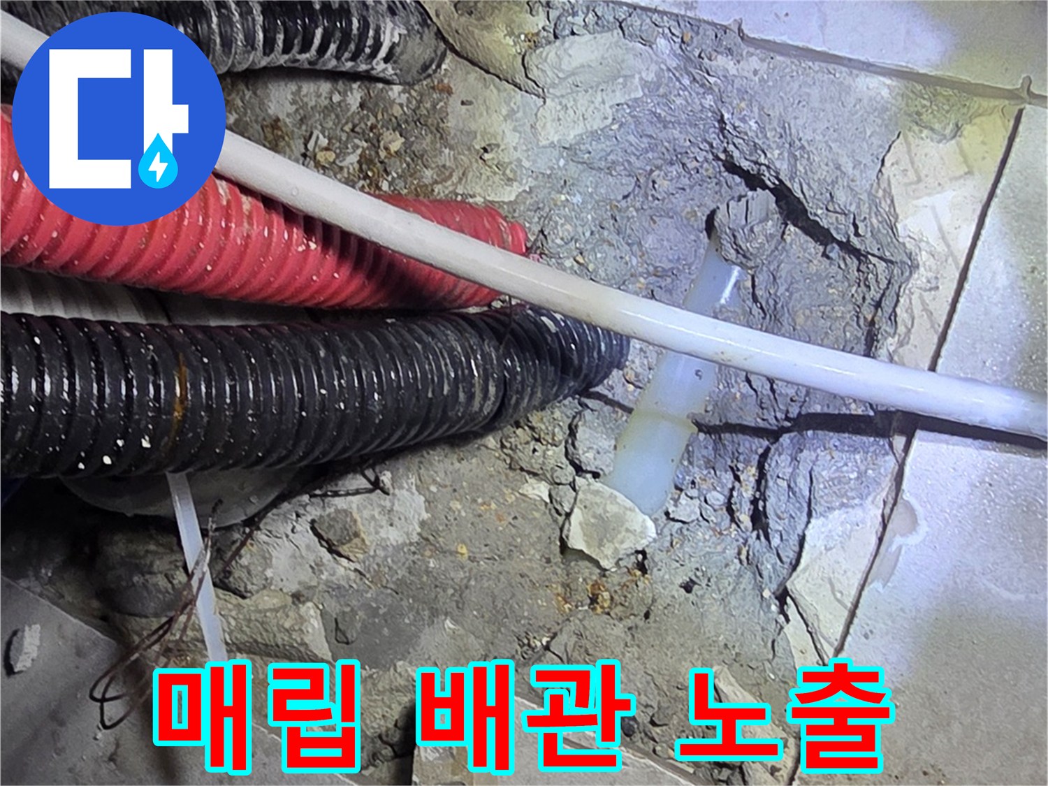 콘크리트 층 아래에 드러난 빨간색 주름관과 검은색 배관의 상태