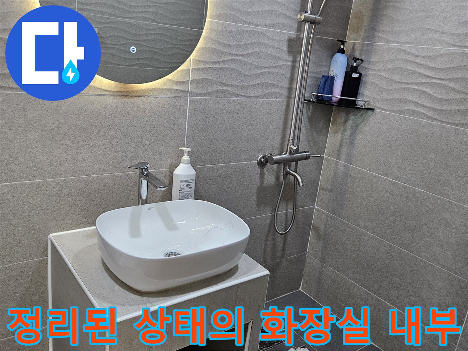 세면대와 수전이 설치된 회색 타일 욕실 공간
