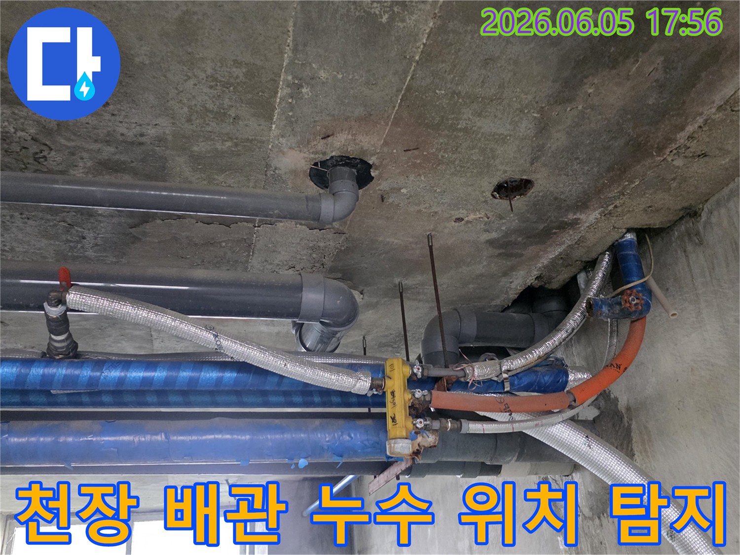다양한-배관들이-복잡하게-얽혀-있는-콘크리트-천장-아래-누수-탐지-전문가가-현장을-점검하는-모습