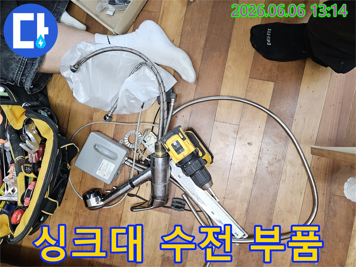 수도꼭지 교체 작업을 위한-새로운 수전과-연결 호스-그리고 전동 공구가 바닥에 펼쳐진 현장입니다.