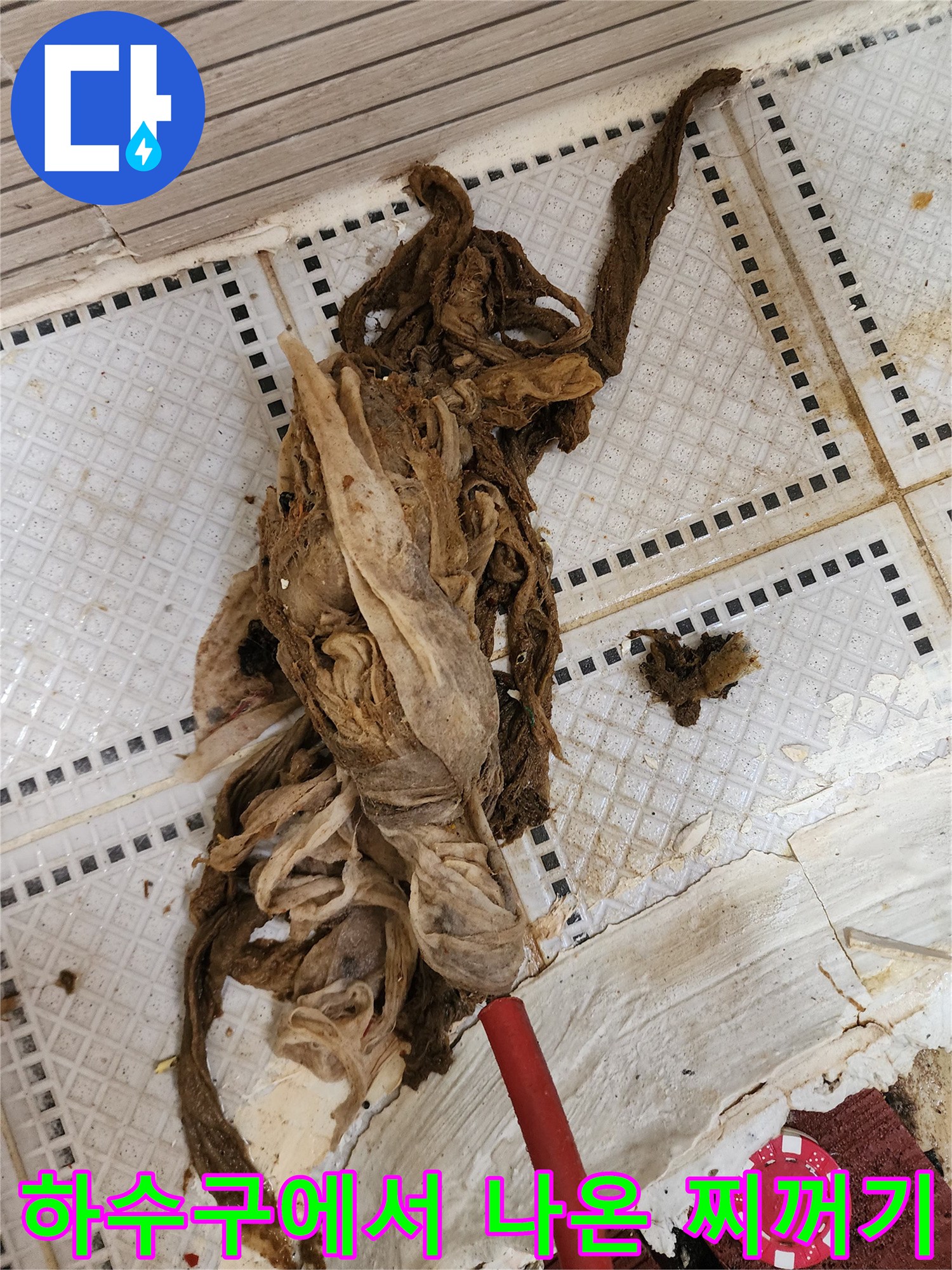 배관 작업 후 타일 위에 놓여 있는 갈색 섬유질 슬러지