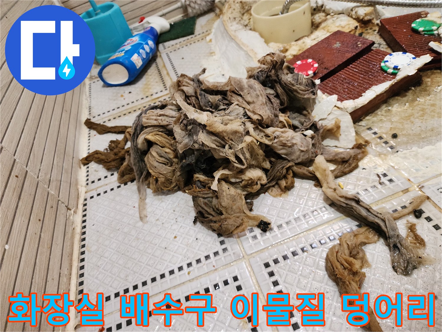 화장실 바닥 타일 위에 쌓여있는 거대한 머리카락과 섬유 슬러지 뭉치