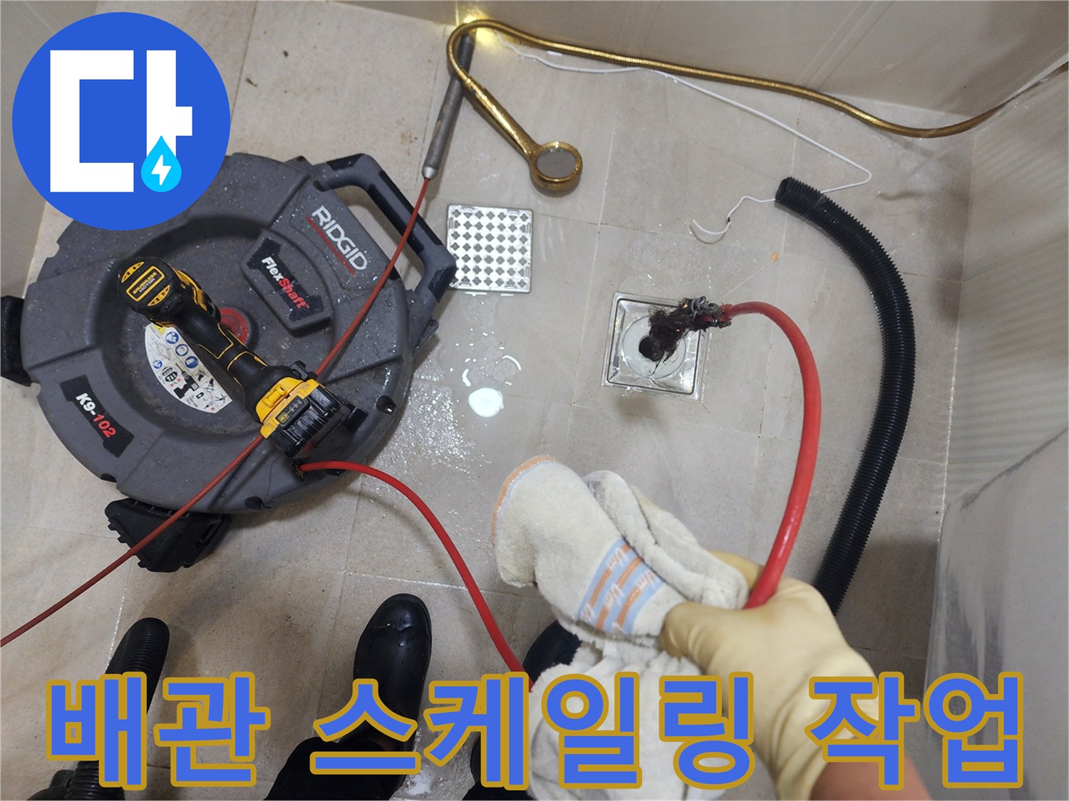 빨간색 케이블이 연결된 배관 청소 장비가 배수구로 들어가는 장면