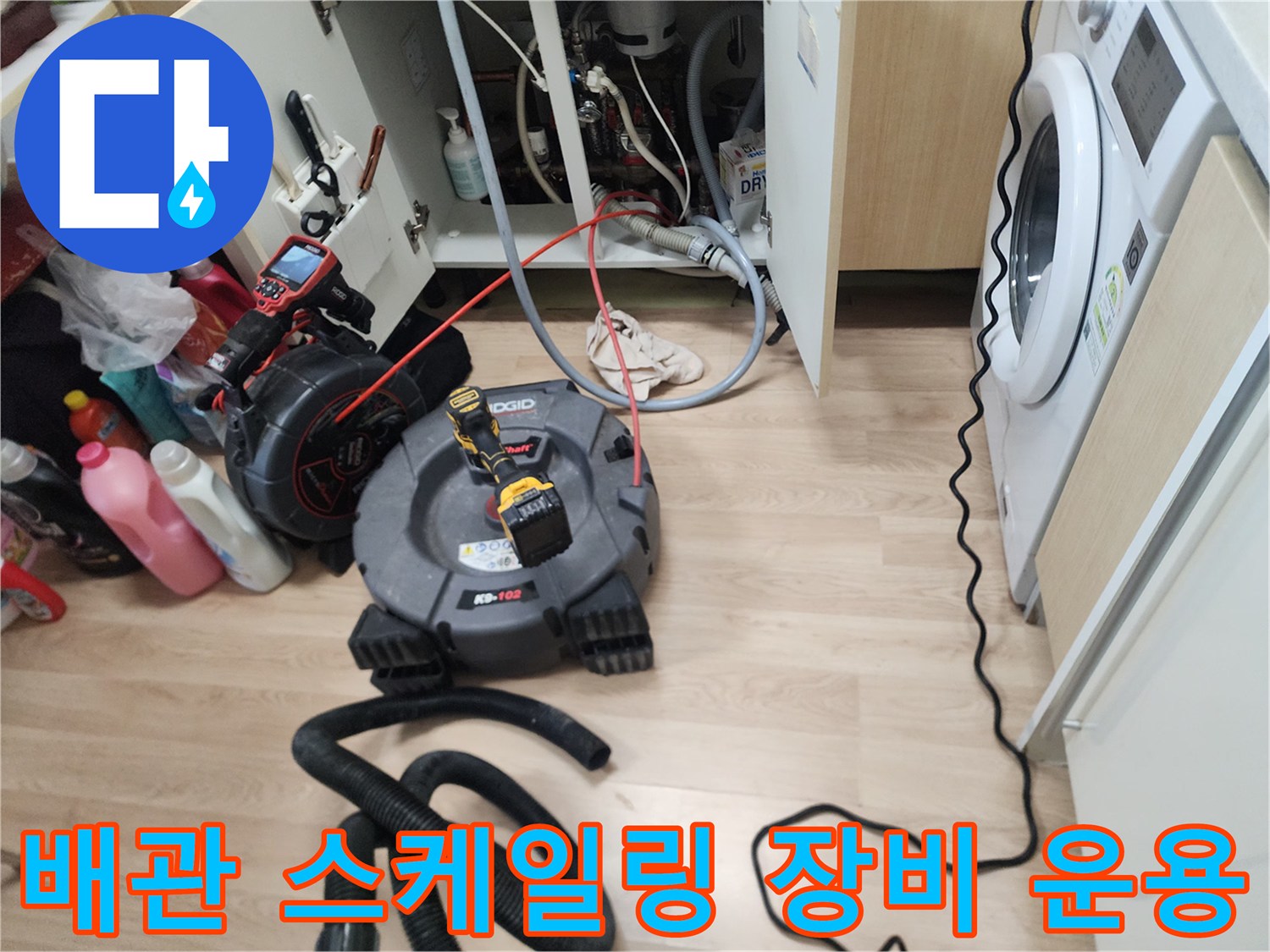 싱크대 하부장 내부의 막힌 배관을 뚫기 위해 가동 중인 전문 장비