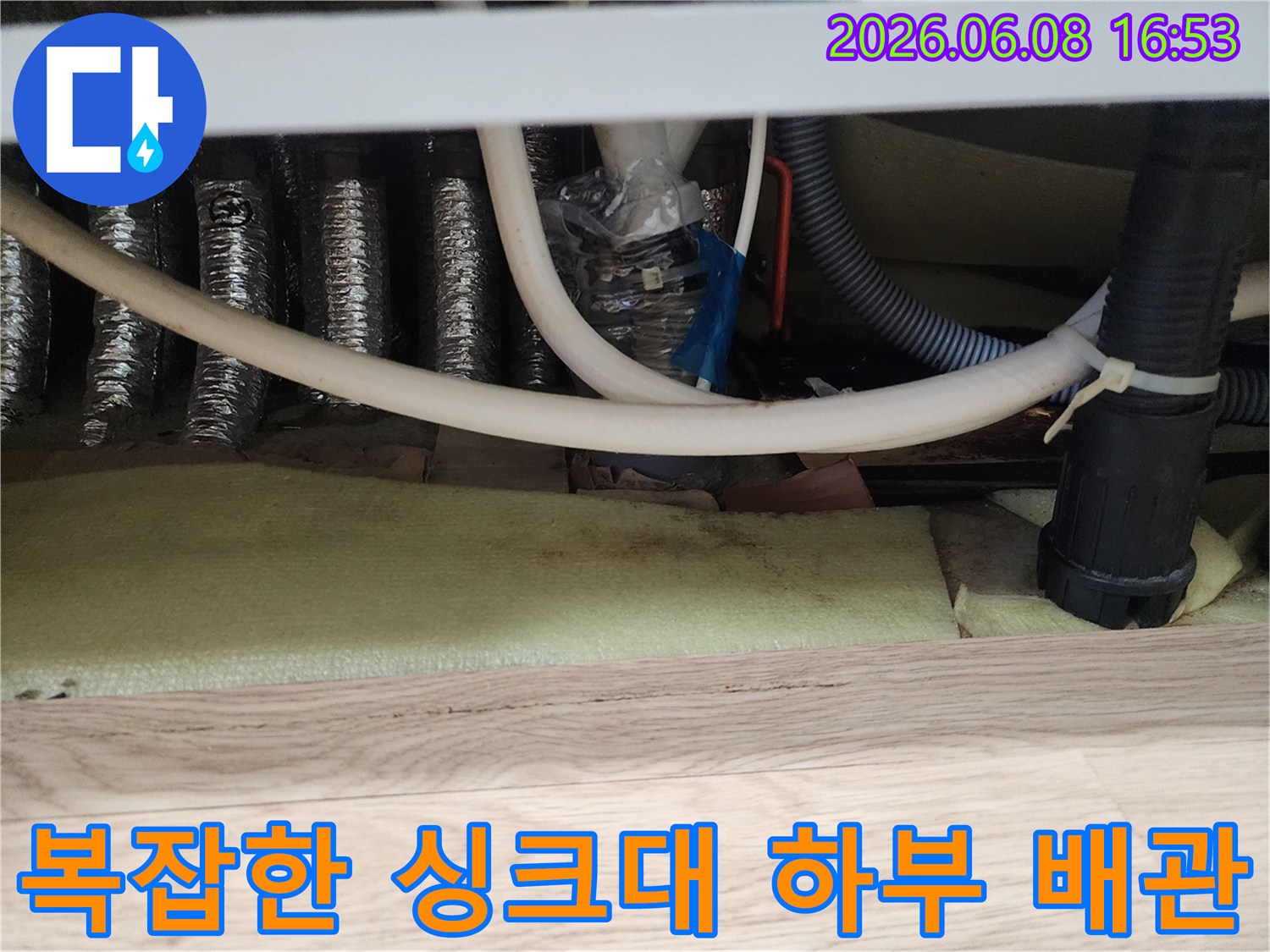 여러 갈래로 연결된 싱크대 하부의 은색 자재 및 호스들