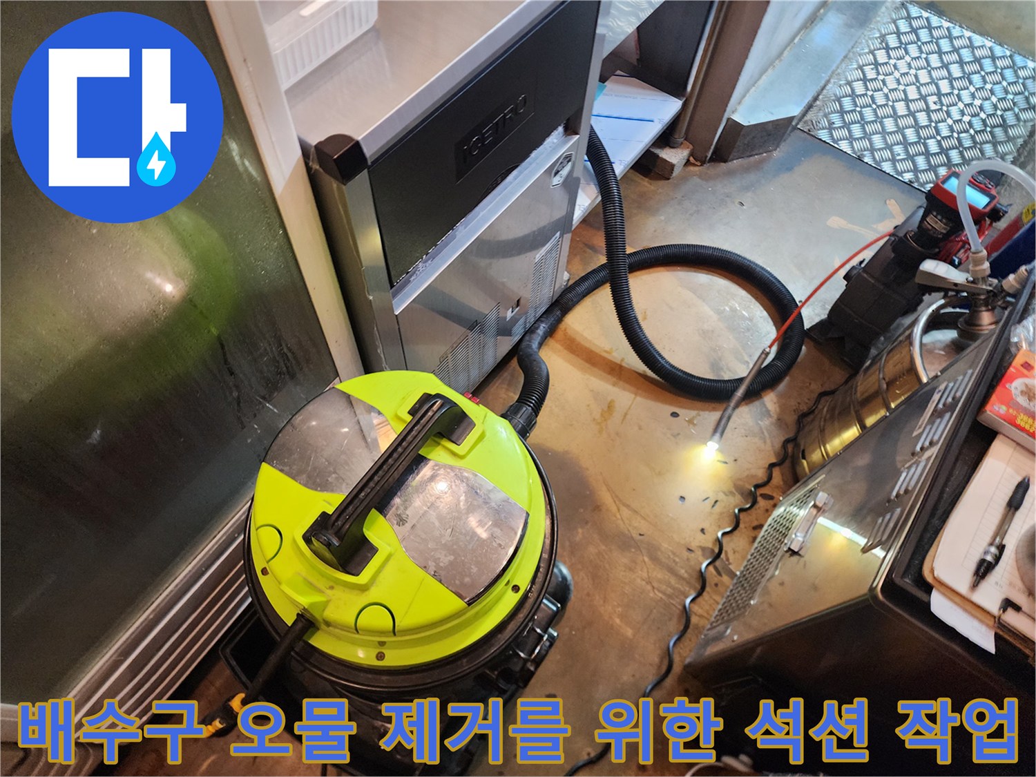 석션 장비와 호스가 연결된 주방 바닥 작업 현장