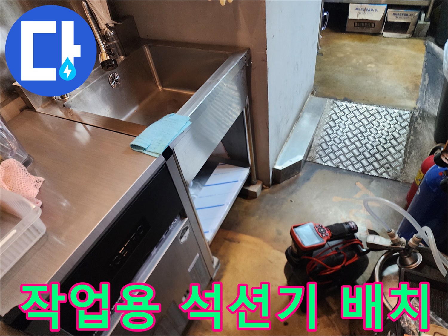 스테인리스 싱크대 아래에 설치된 배관 청소 장비