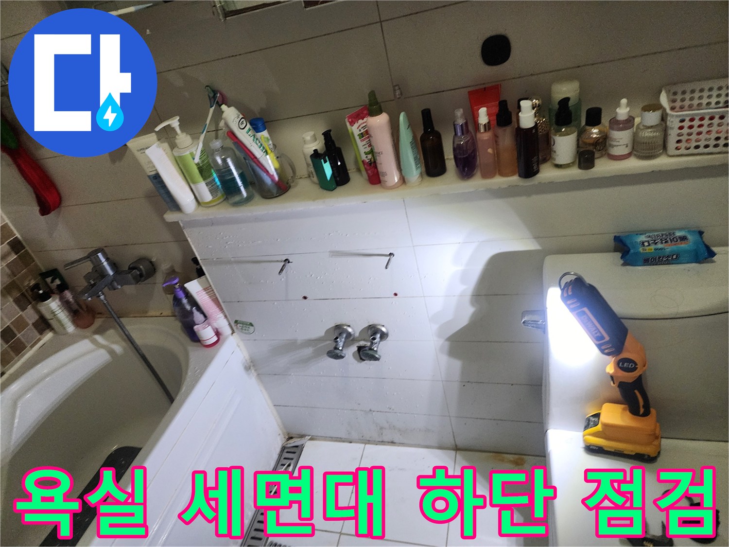 양주 고읍동 욕실 세면대 아래쪽 배관 부근을 손전등으로 비추며 점검하는 모습
