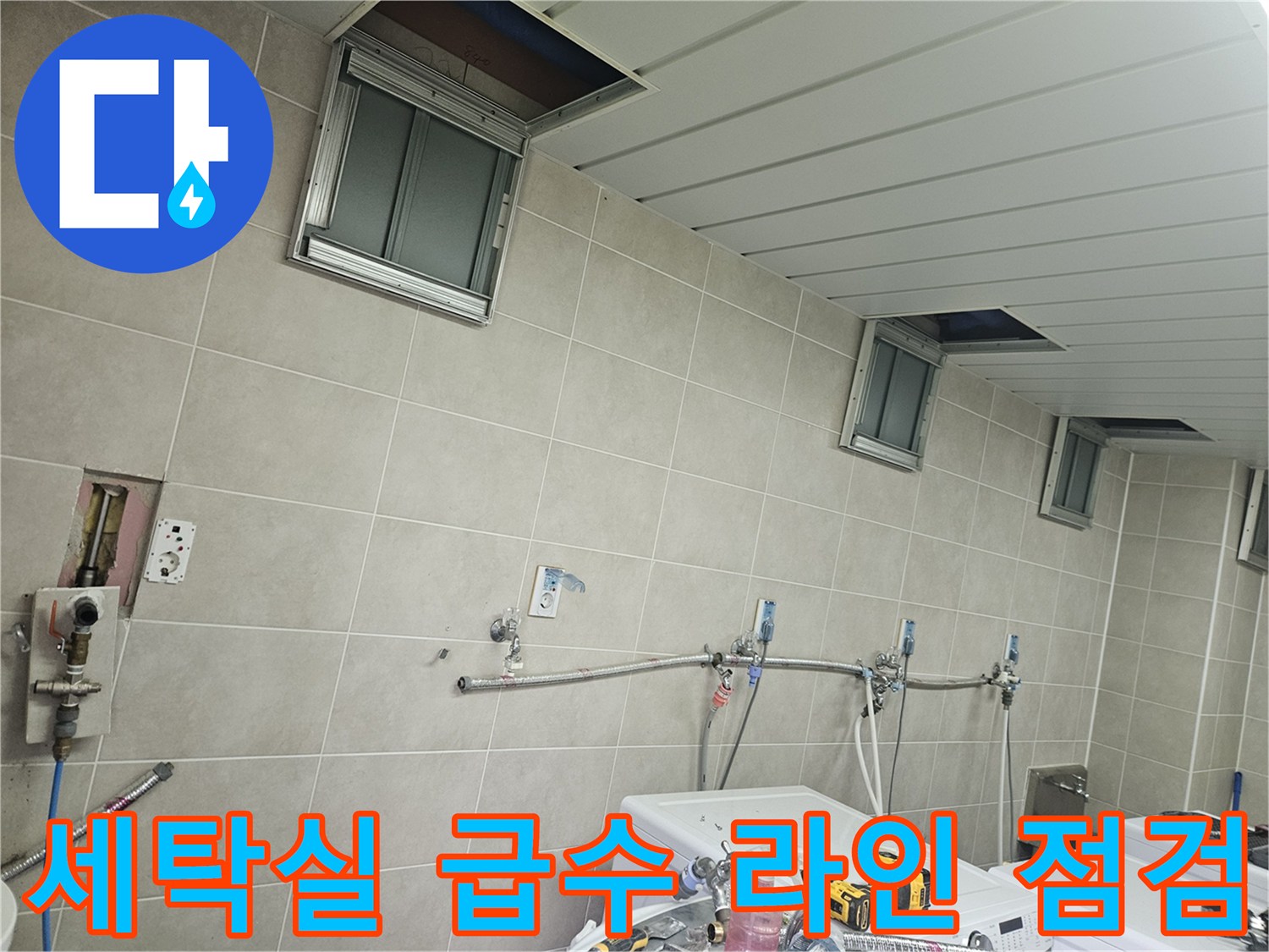 세탁실 타일벽에 설치된 수도 배관과 연결 부품들