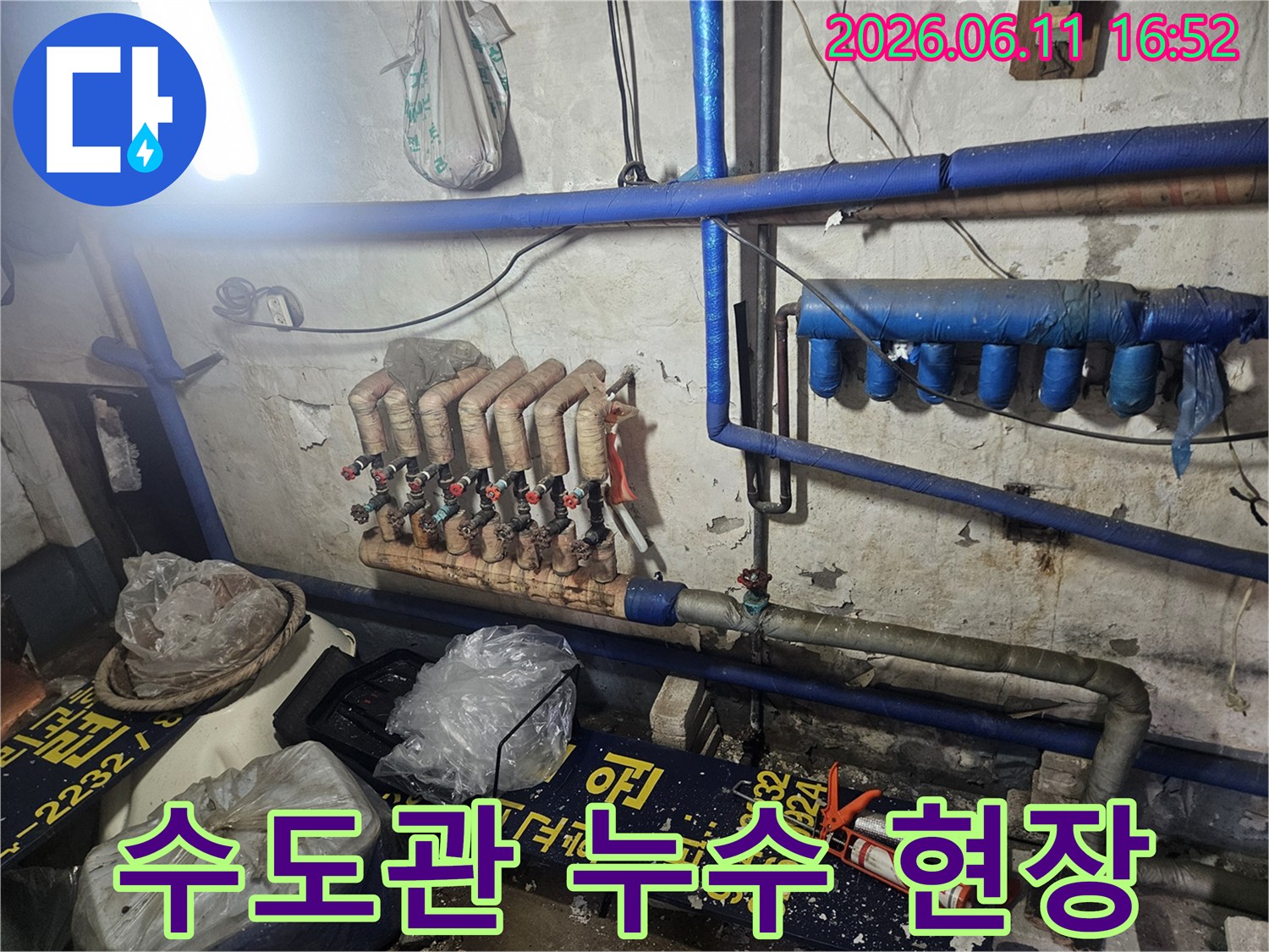 지하 공간에 설치된 복잡한 수도 배관과-난방 분배기의 현재 상태를 보여주는-현장 사진입니다.