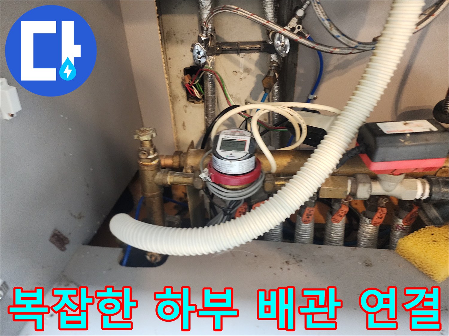 싱크대 하단부에 설치된 금속 배관과 유량계 장비 모습입니다.