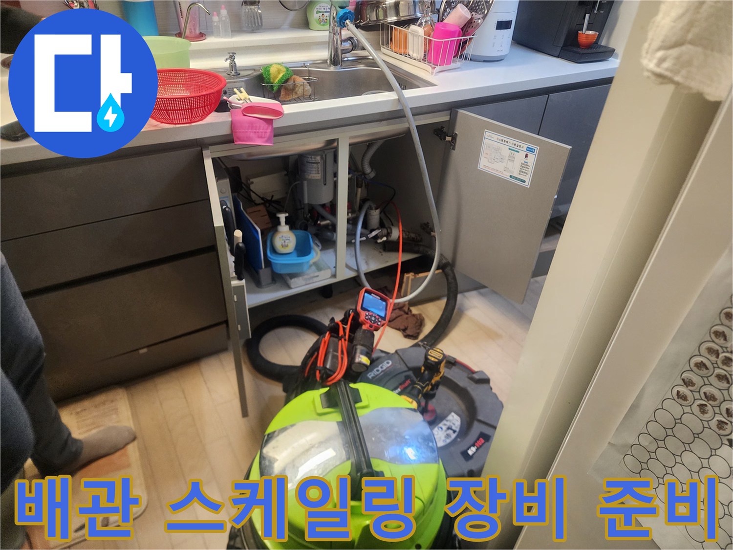 주방 싱크대 밑 배관 청소를 위해 배치된 습식 석션기 및 전문 장비