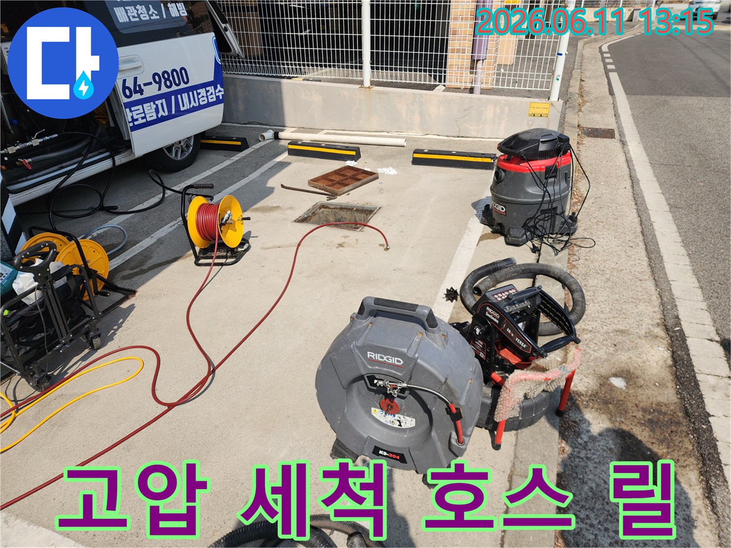 맨홀 옆에 배치된 노란색 호스 릴과 고압 세척기 장비 모습