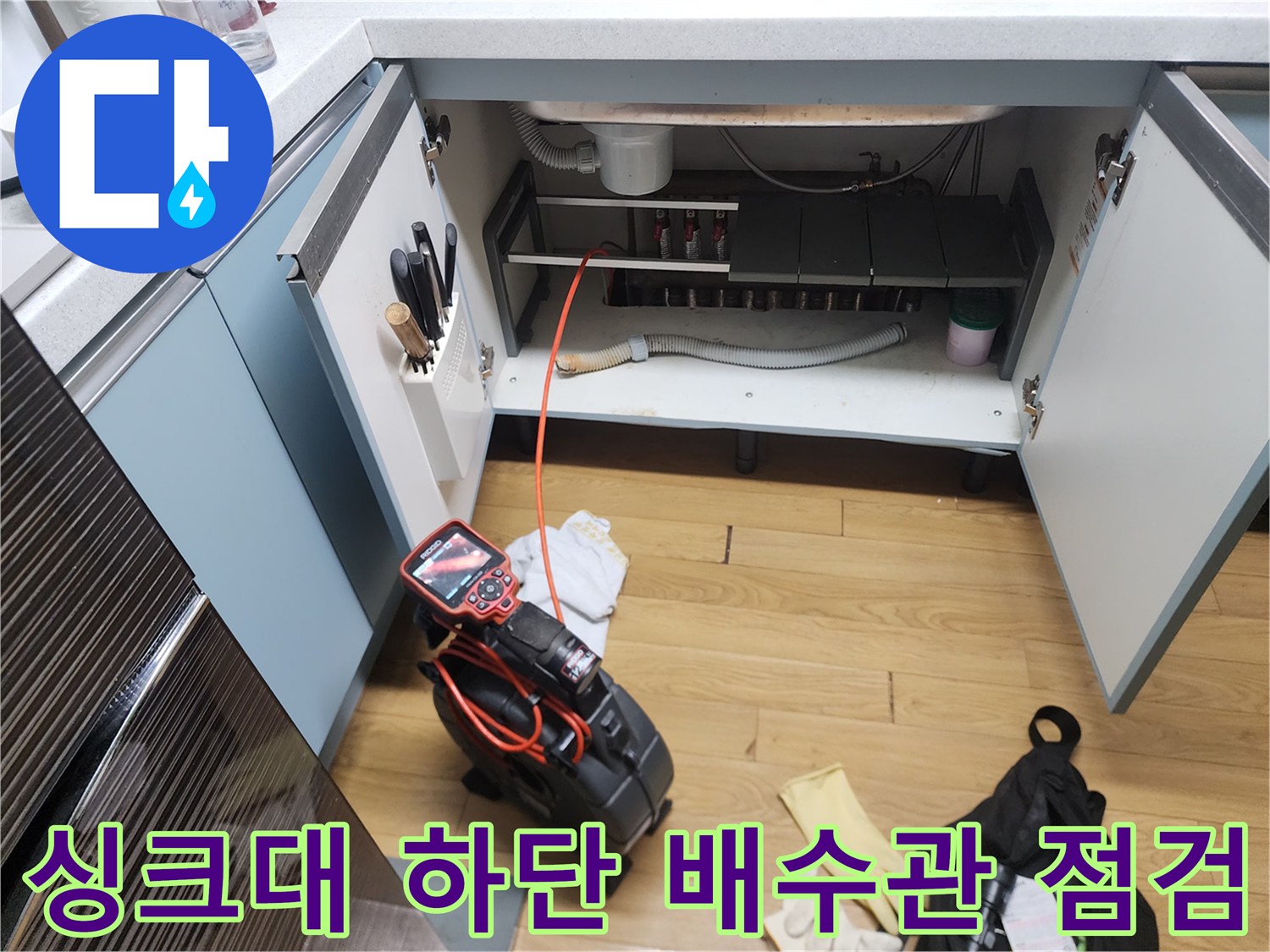 광진구 중곡동-주방 싱크대 하부장 내부의 배수관과 작업 장비 모습