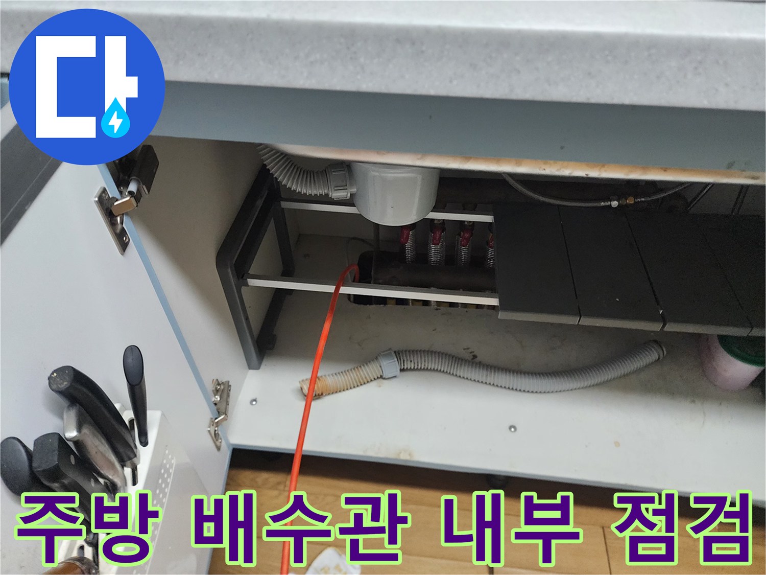 싱크대 하단부의 배수 호스와 굵은 배관 연결 부위 근접 사진