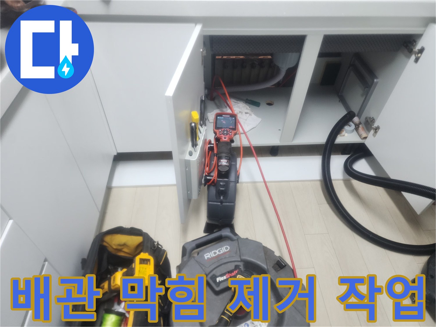 싱크대 아래 배관 청소를 위해 연결된 샤프트 장비와 호스 연결부