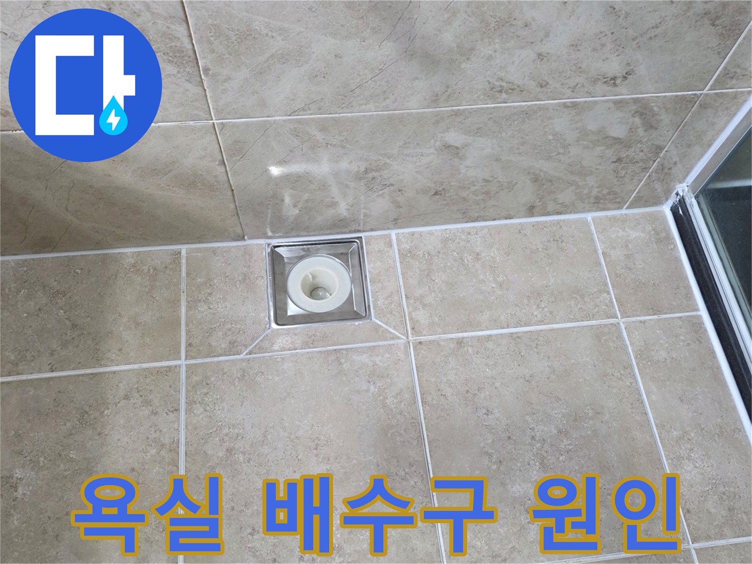 깨끗하게 시공된 욕실 타일 중앙에-사각형 배수구가 위치하며-주변 마감 상태를 면밀히 관찰하는 사진입니다