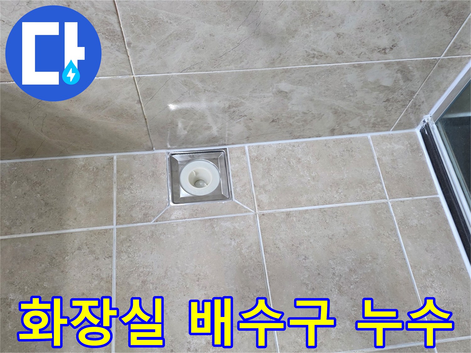 욕실 바닥에 설치된-사각형 스테인리스 배수구-주변 타일과 백시멘트 마감 상태를 보여주는 이미지입니다