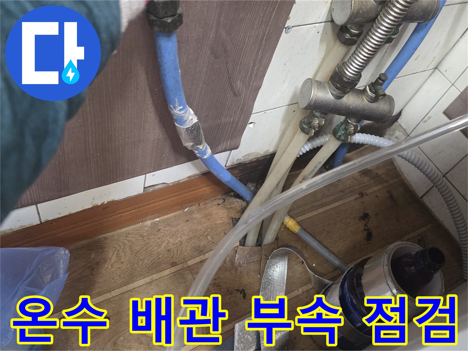 금속 재질의 분기 밸브와 파란색 배관이 연결된 수도 부속품 근접 사진입니다.