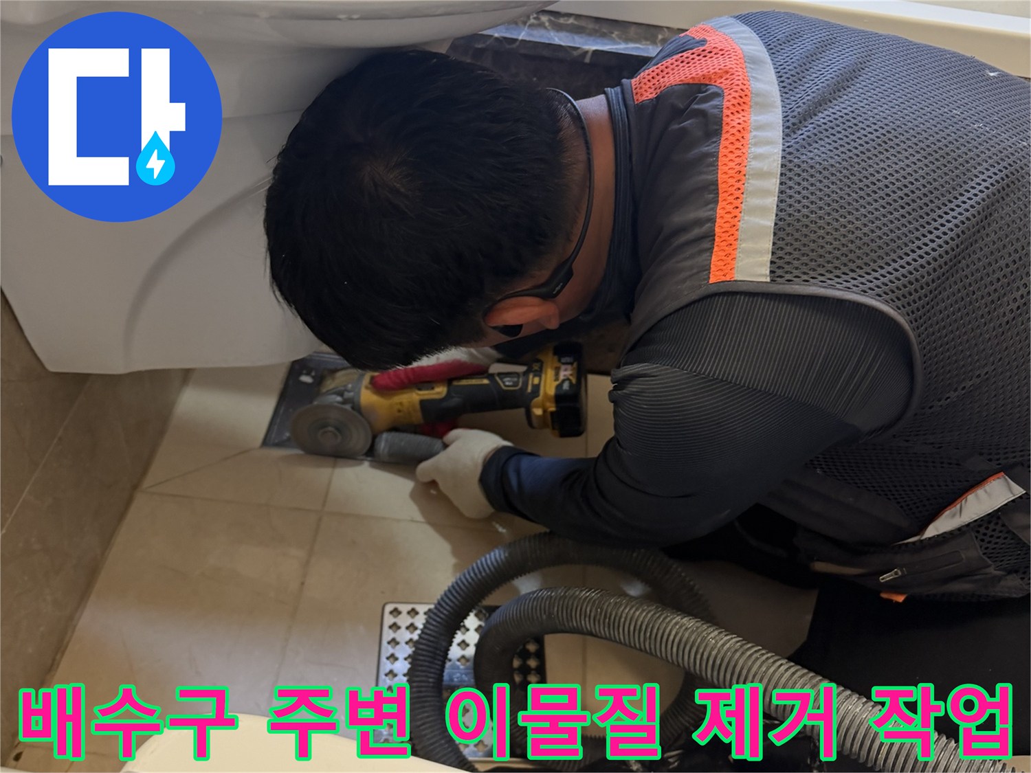 그라인더와 진공청소기를 활용하여 욕조 배수 부근의 잔여물을 청소하는 엔지니어의 모습