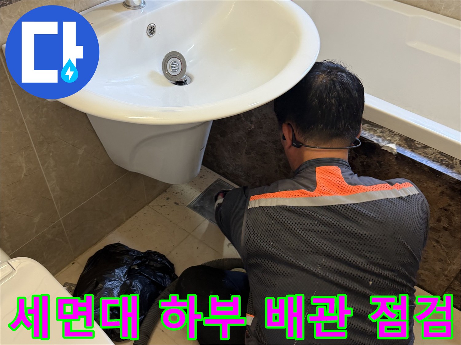 엔지니어가 세면대 아래쪽 배수구 부근을 꼼꼼하게 조사하고 있습니다.