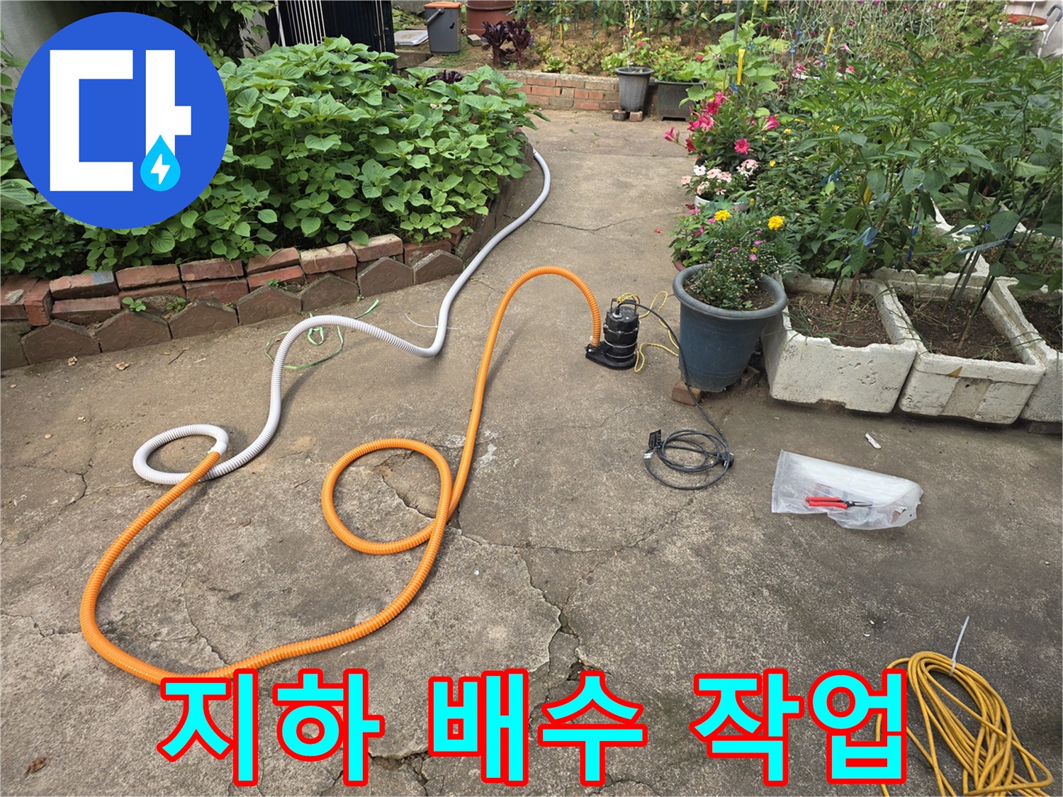 지하 공간의 고인 물을 제거하기 위해 배수 호스와 펌프를 설치한 모습입니다.