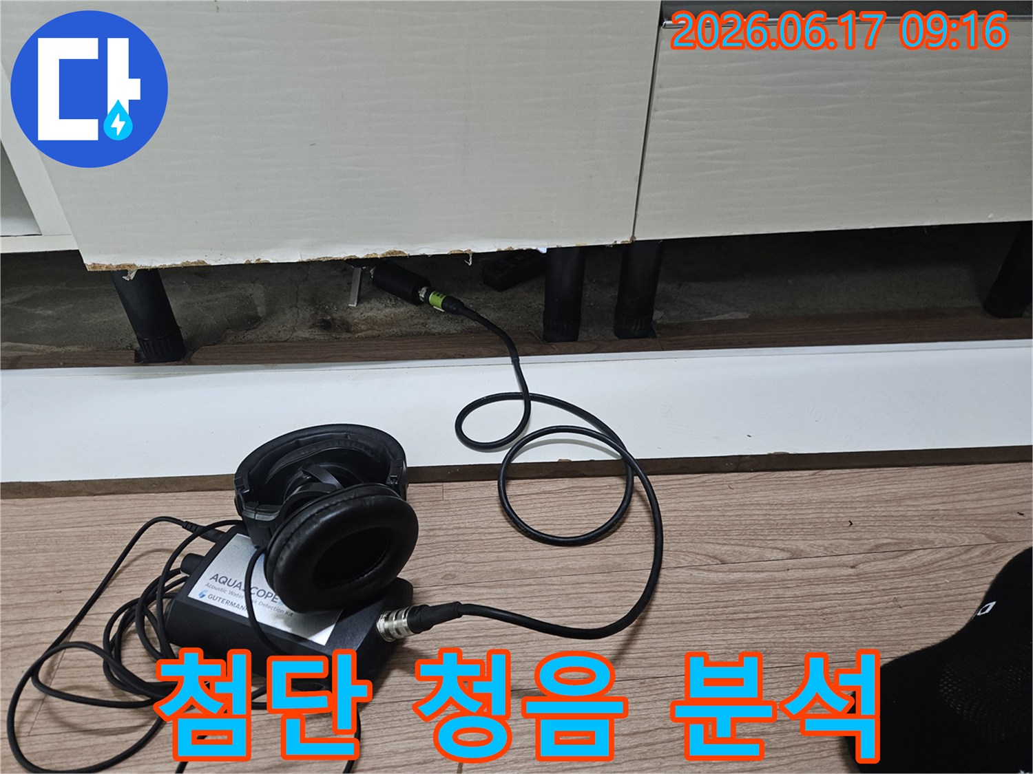 누수 탐지 전문가가-첨단 청음식 장비를 사용하여-싱크대 하부 배관의 누수음을 분석하는 장면