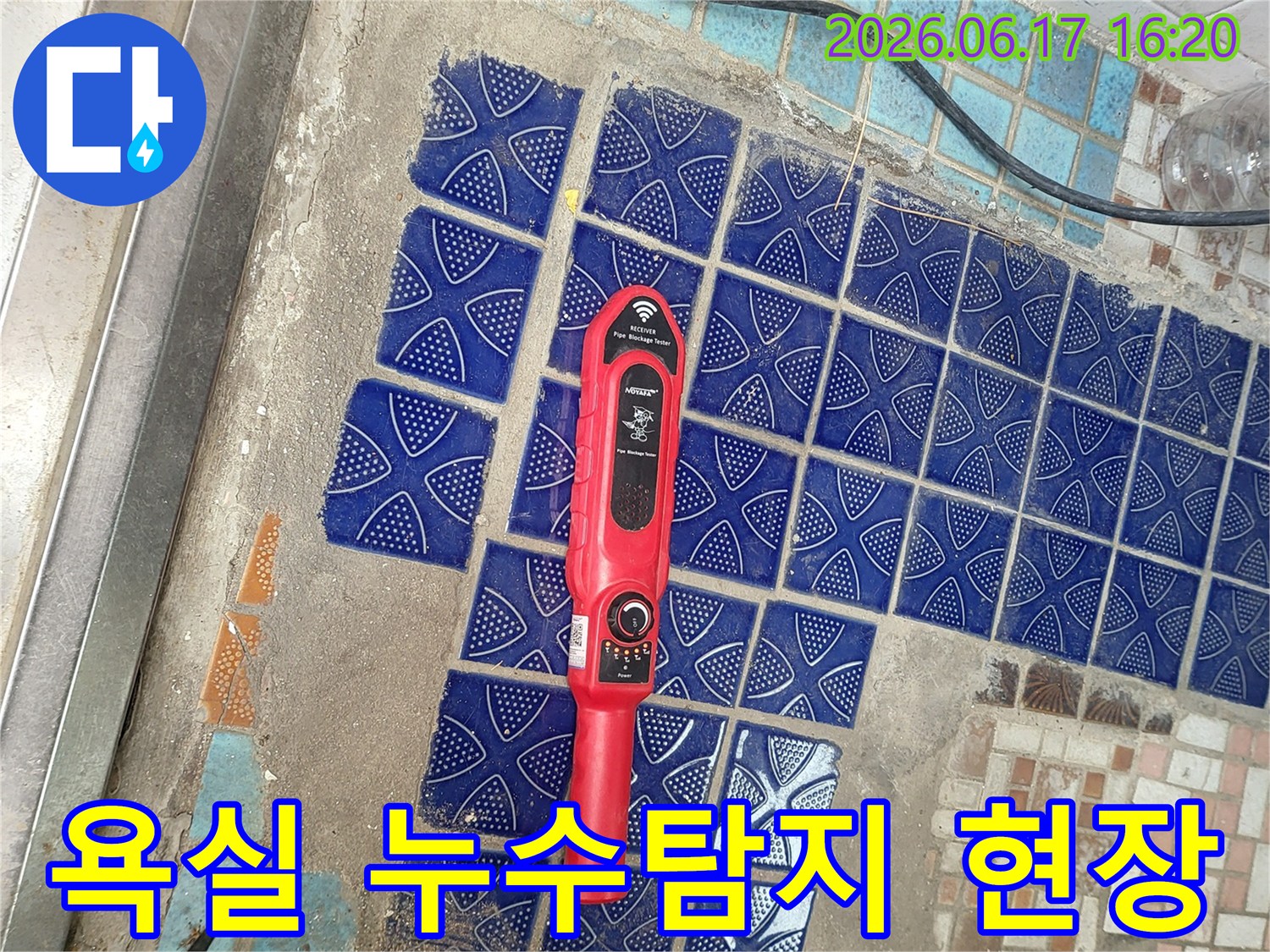 붉은색 누수탐지 장비가 파란색 욕실 타일 위에 놓여-정밀한 누수 원인 파악 중인 모습